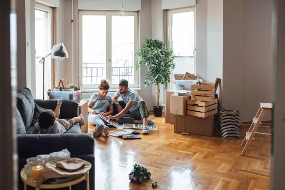 Man, woman, and child in apartment with moving boxes and crates.